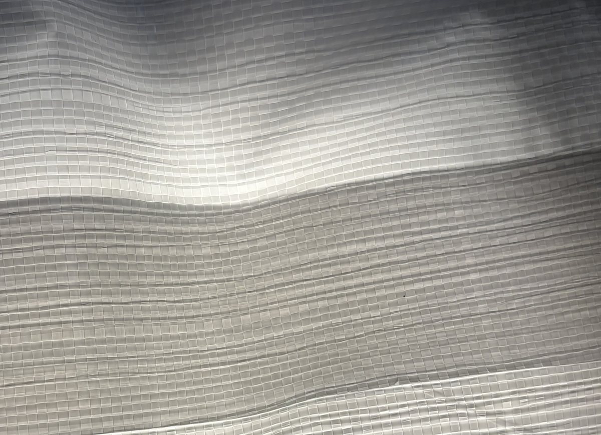 Close-up of a Fusion heat-sealed seam on the same woven fabric, backlit, showing a solid continuous bond with no needle holes